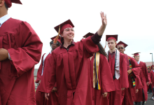 A student waves to family during graduation.