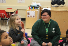 Preschool teacher sits with a student