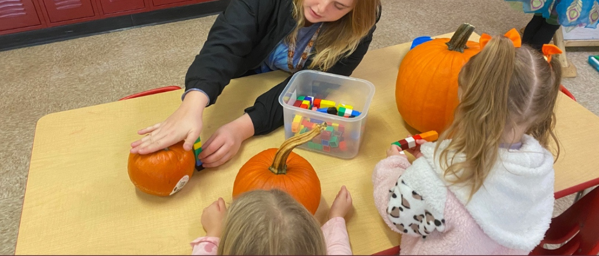Students carving pumpkins with teacher